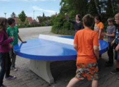 Mehrere Schüler spielen an der runden Tischtennisplatte
